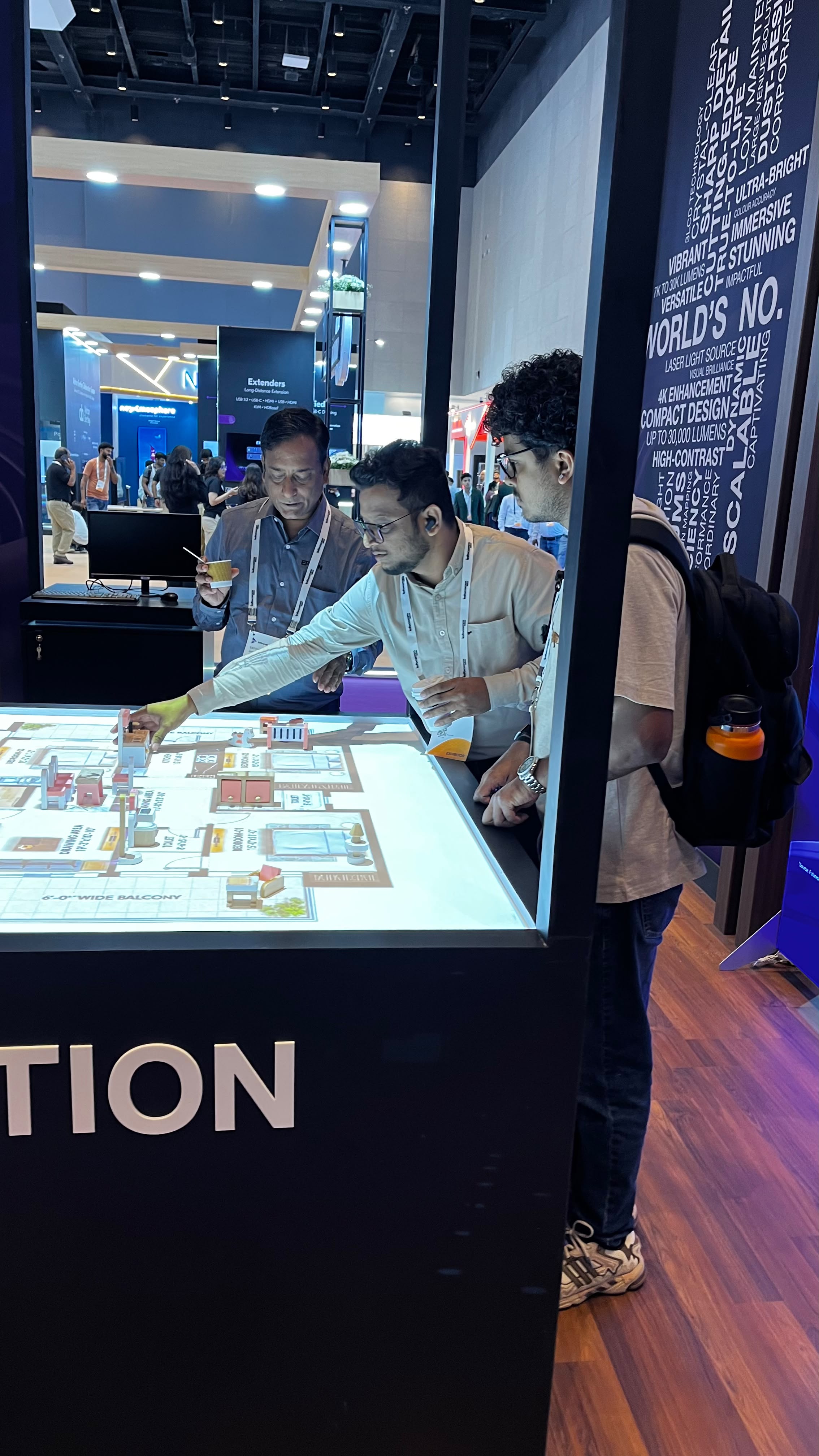 Visitors exploring a projected tabletop floor plan with physical models